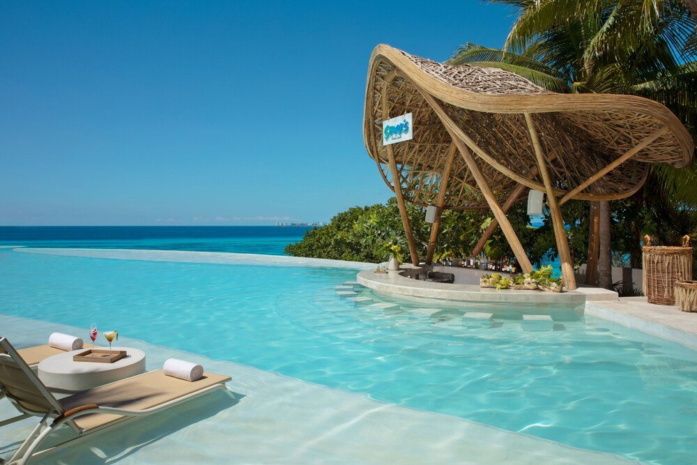 Impression Isla Mujeres by Secrets, piscina ao ar livre com espreguiçadeiras e guarda-sóis